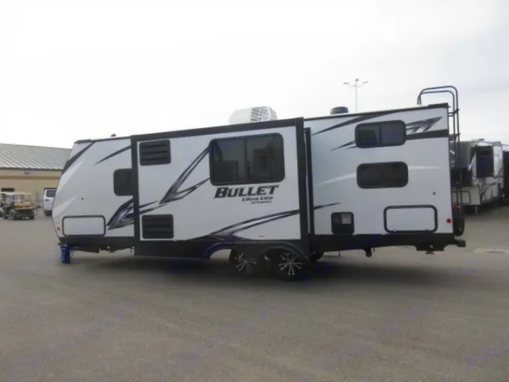 This white Bullet Ultra Lite travel trailer, an excellent RV rental option, is ready for camping adventures. Parked on asphalt with slide-out extended.. Other Bullet 2021