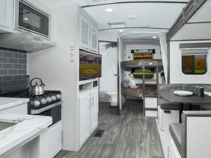 Modern RV rental interior with kitchen, dinette, bunk beds, and bathroom, offering comfort and convenience for travel.. Other Bullet 2021