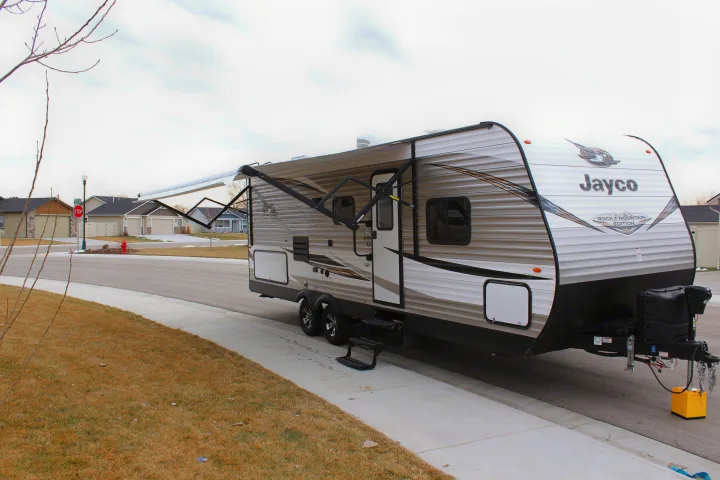 Jayco travel trailer RV rental with awning extended on a suburban street, ideal for your next trip.. Jayco Jay Flight SLX Rocky Mtn Edition 2019