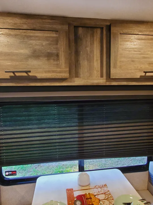 Inside an RV rental: light wood cabinets, dark pleated window blinds, and a cozy dinette table set with an autumn-themed placemat.. Forest River Salem 2020