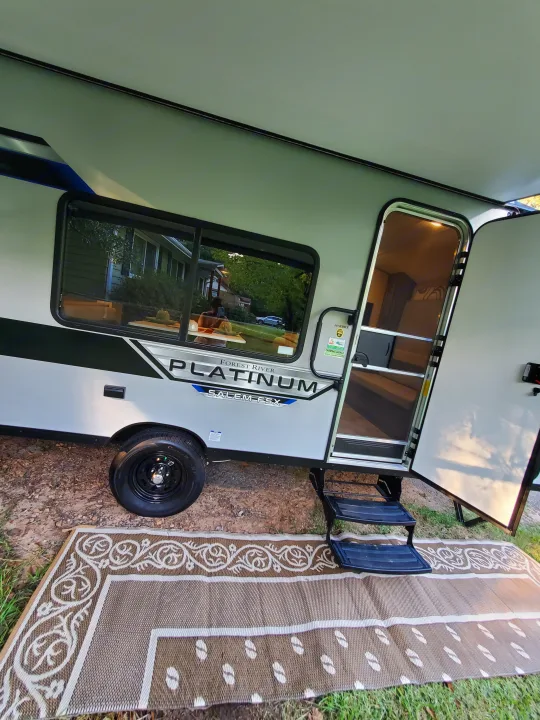 Modern light gray RV rental with open door, steps, an extended awning, and ground mat ready for your trip.. Forest River Salem 2020