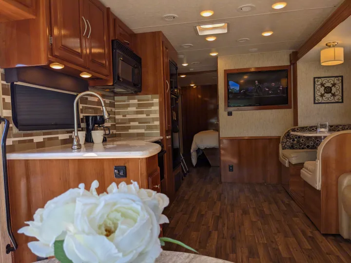 Well-appointed rv rental interior featuring a full kitchen, dining nook, TV, and cozy bedroom.. Coachmen Mirada 2019
