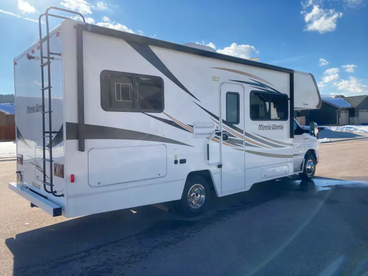 This bright white Winnebago Minnie Winnie Class C RV rental, equipped with a ladder and awning, awaits your next adventure.. Winnebago Minnie Winnie 2016