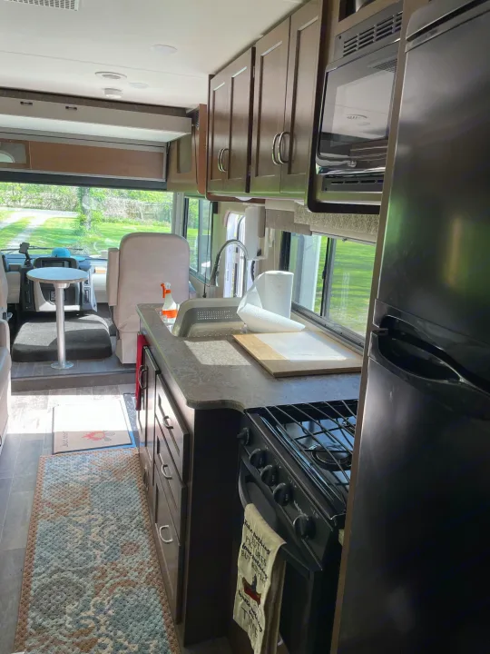 Spacious RV rental interior featuring a full kitchen with stove, sink, microwave, and fridge, plus front living/driving area.. Winnebago Intent 2019