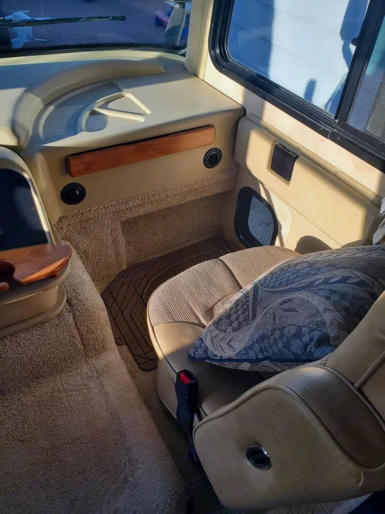 Pillow on comfortable tan passenger seat in this rv rental. Carpeted floor, dashboard, and sunny window view.. Allegro Allegro Motorhome 2009