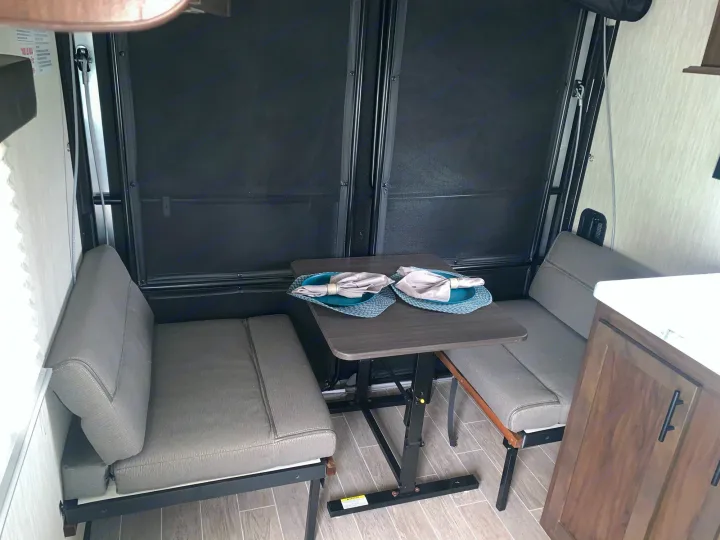 RV rental dinette area with table and benches, set for two, facing a screened back ramp.. Forest River Wolf Pup 2021