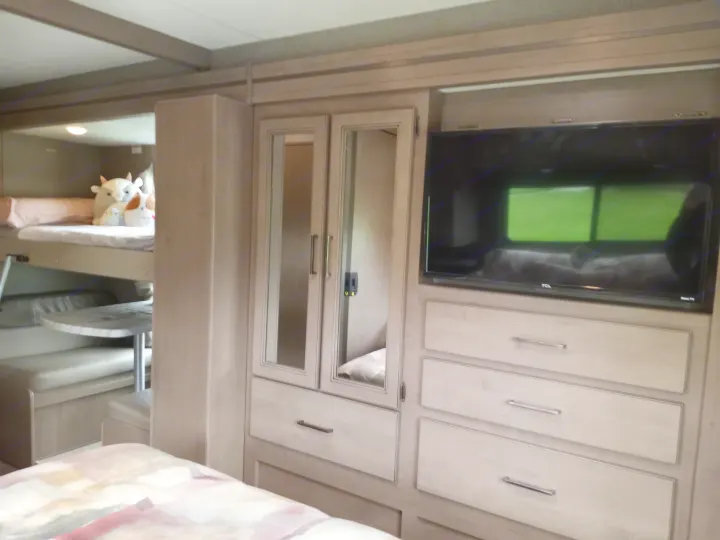 Inside this RV rental: bunk beds, a dinette, and a TV entertainment unit with ample storage. Ideal for families.. Coleman Thor 2021