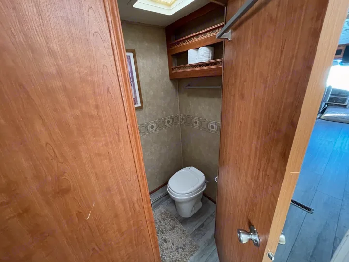 A private, compact bathroom in an RV rental, featuring a toilet, storage shelves, and a skylight for natural light.. Forest River Georgetown 2007