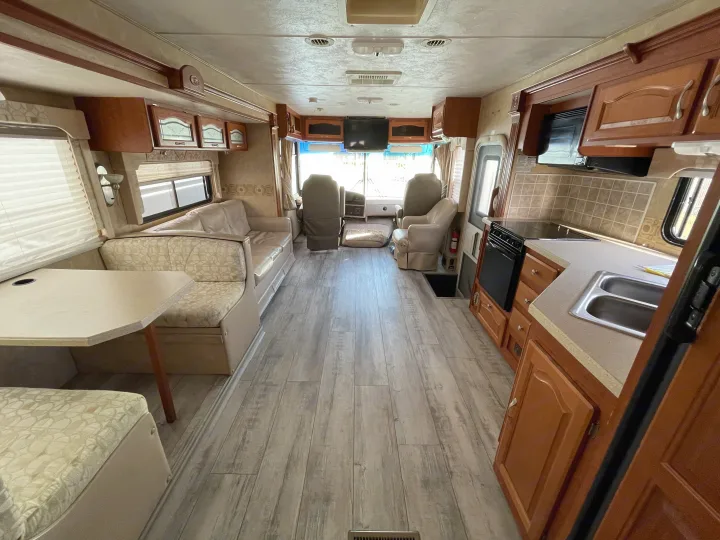 Spacious RV rental interior featuring a full kitchen, dinette, and comfortable seating with modern wood-look flooring.. Forest River Georgetown 2007