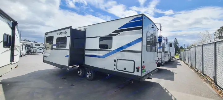 A SportTrek travel trailer with slide-out extended, among other RVs in an outdoor lot. Excellent for rv rental adventures.. Venture Rv Sporttrek 2021