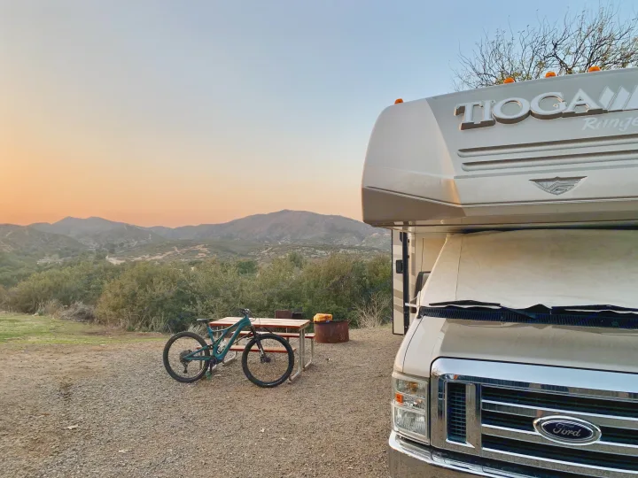 RV rental at a scenic campsite with a mountain bike, picnic table, and fire pit, overlooking mountains at sunset.. Other Other 2010