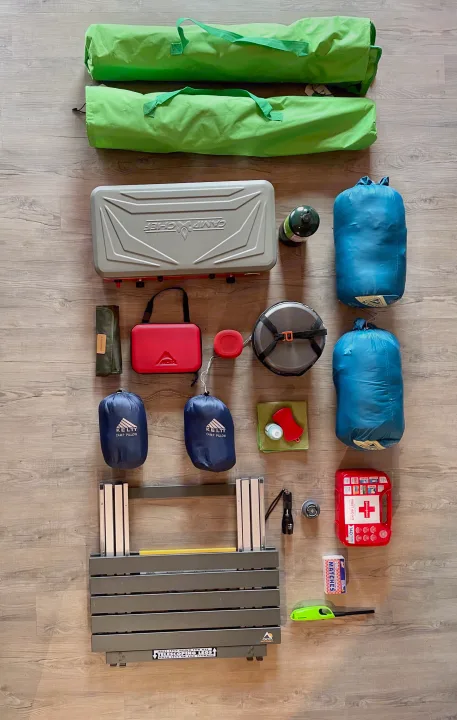 Camping gear laid out for an RV rental trip: stove, cookware, sleeping bags, pillows, and first aid supplies.. Jeep Gladiator Unlimited 2020