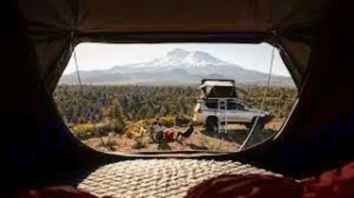 From inside a tent, a white SUV with a rooftop tent, two people, and a dog are camping by a mountain. Perfect for your next **RV rental** **adventure**!. Jeep Gladiator Unlimited 2020