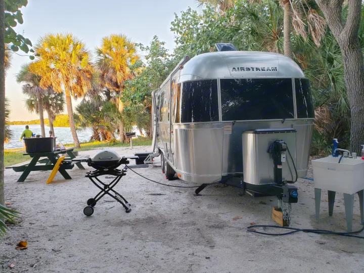 This beautiful RV rental, an Airstream travel trailer, offers a serene waterfront campsite with amenities like a grill and picnic table.. Airstream Flying Cloud 2020
