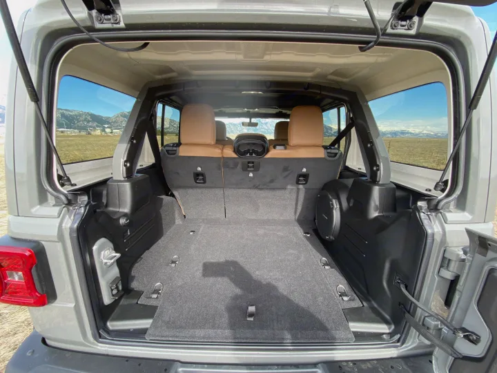 Spacious grey Jeep SUV rear cargo area, ready for adventure or RV rental. Tan seats, subwoofer, and mountain views.. Jeep Wrangler Unlimited 2021