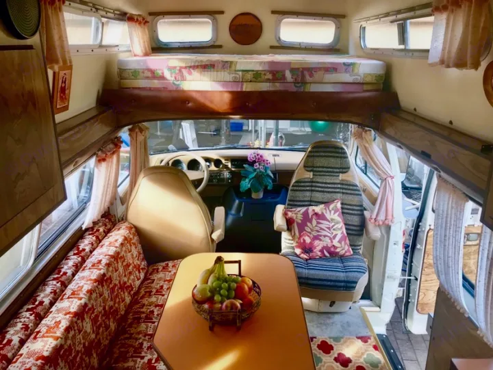Cozy vintage RV rental interior featuring an over-cab bed, dining area, and front cabin view.. Frontier Other 1979