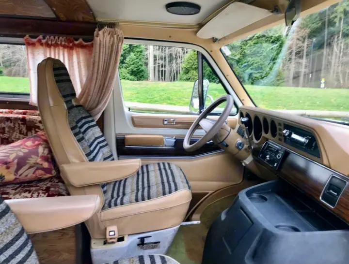 Explore a cozy vintage RV rental interior! Features spacious driver's area, patterned seats, wood trim, and scenic views.. Frontier Other 1979