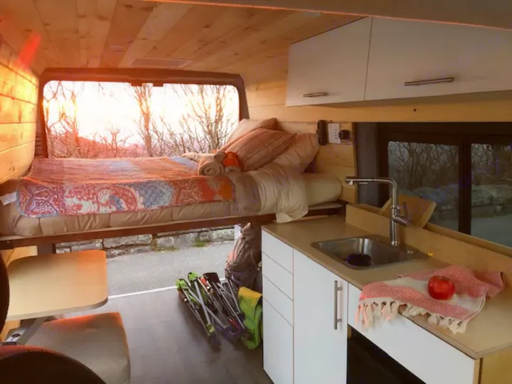 Cozy RV rental interior with a comfy bed, kitchen, and stunning sunset views. Perfect for travel adventures!. Ram Promaster 2021