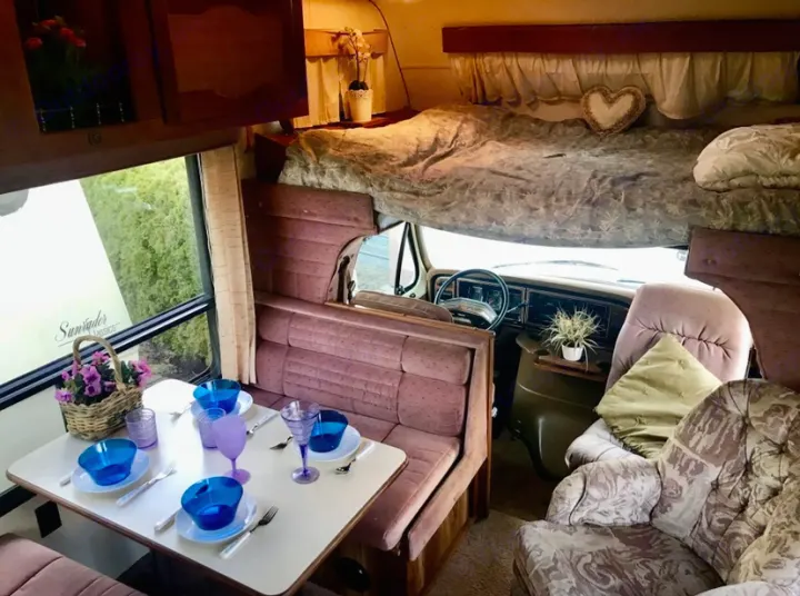 Cozy RV rental interior: overhead bed, set dining table, and lounge area. Enjoy comfort and functionality on your next adventure.. Ford Econoline 1988
