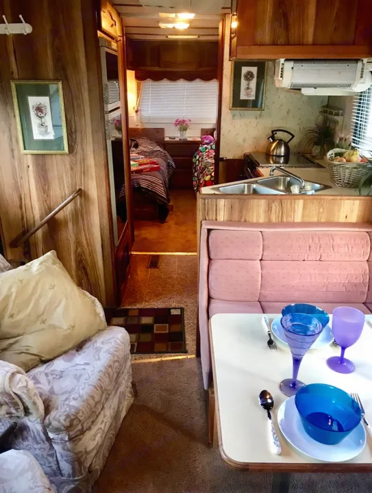 RV rental's inviting interior features a set dining table, kitchen, and a glimpsed bedroom. Perfect for travel comfort.. Ford Econoline 1988