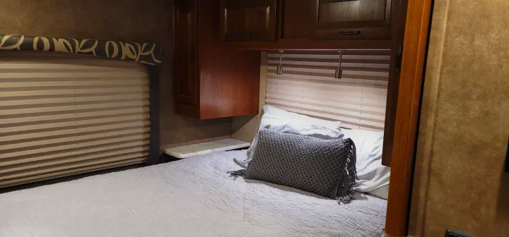 Inside an RV rental: a comfy bedroom with storage cabinets, window blinds, and reading lights over the bed.. Forest River Other 2015
