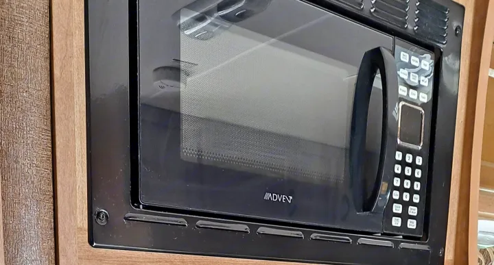 A black Advent microwave oven, built into the cabinetry of an RV rental. Essential kitchen appliance.. Coachmen Freelander 2015