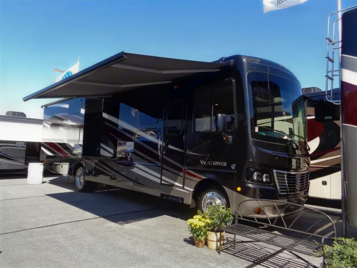 A large, luxury black and grey Vacationer motorhome with an extended awning, perfect for an RV rental adventure.. Holiday Rambler Vacationer 2017