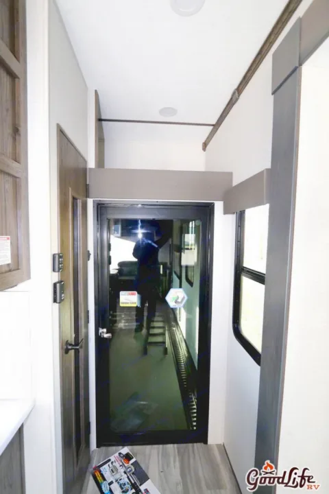 RV rental interior: Bright hallway with a glass door, reflecting a person. Features modern wood accents and ceiling lights.. Alliance RV Valor 40V13 2021