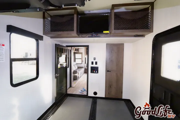 Inside an rv rental: toy hauler garage with utility floor, TV, netted storage, and connected living space.. Alliance RV Valor 40V13 2021