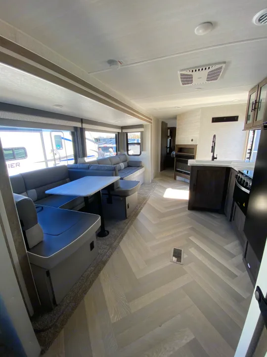 Inside this spacious RV rental, a comfy U-shaped dinette faces a well-equipped kitchen, all on modern herringbone flooring.. Forest River Wildwood 2021