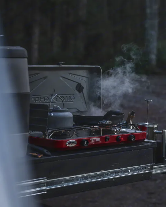 Enjoying outdoor cooking from an RV rental. Steam rises from a kettle and pan on a Teton stove, set up for a camping adventure.. Toyota 4Runner 2021