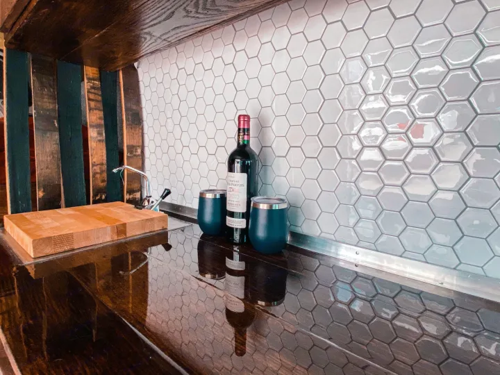 Sleek RV rental kitchenette: hexagonal tiled backsplash, wooden counter, cutting board, wine, and cups. Ready for adventures!. Ram Promaster 2020