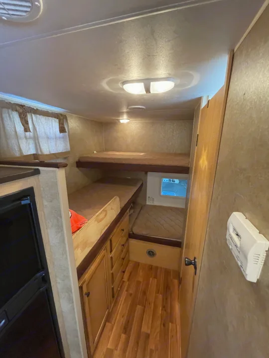 RV rental: compact bunk room with two beds, wood flooring, a window, and adjacent kitchen cabinetry.. K-Z Manufacturing Spree Ultra-Lite 2012