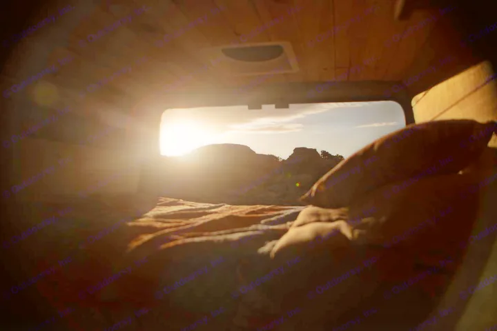 Wake up to desert views from your RV rental! Cozy bed inside, with sun over mountains through the window.. Ram Promaster 2021
