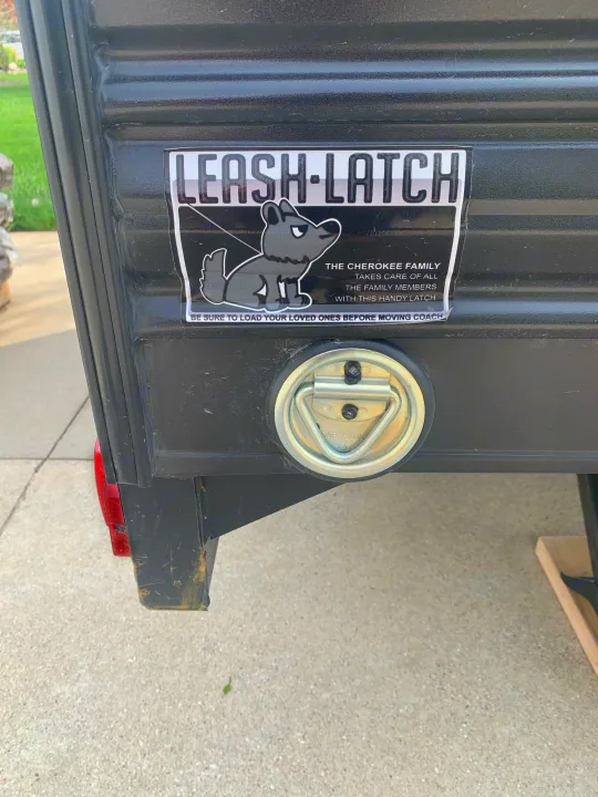 An RV rental trailer features a "LEASH-LATCH" pet sticker and a sturdy 1500lb capacity tie-down on its rear.. Forest River Wolf Pup 2021