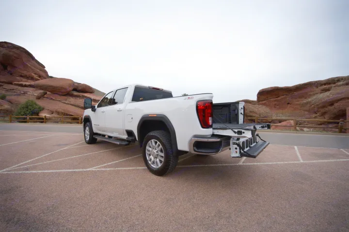 White GMC Sierra HD pickup, tailgate deployed, at scenic red rocks. Ideal for your next rv rental towing trip.. GMC Sierra 2500HD 2021