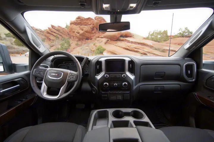 GMC truck interior with dashboard, steering wheel, and scenic mountain view. Great for exploring the outdoors or complementing an rv rental trip.. GMC Sierra 2500HD 2021
