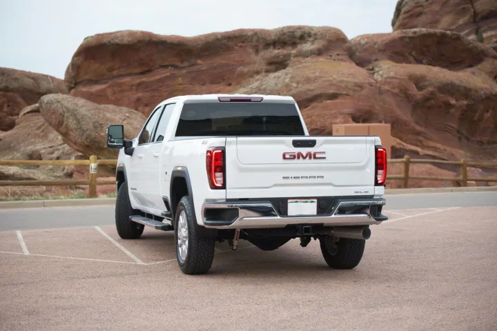 White GMC Sierra pickup truck parked in front of striking red rock formations, ready for your next RV rental trip.. GMC Sierra 2500HD 2021