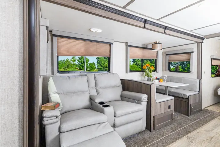 Comfortable RV rental interior with recliners, dining booth, and green outdoor views.. Gulf Stream Envision 2021