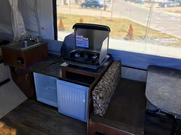 RV rental: Compact camper interior. Kitchen with sink, stove, open fridge, and dinette by large windows.. Forest River 1940 LTD 2018