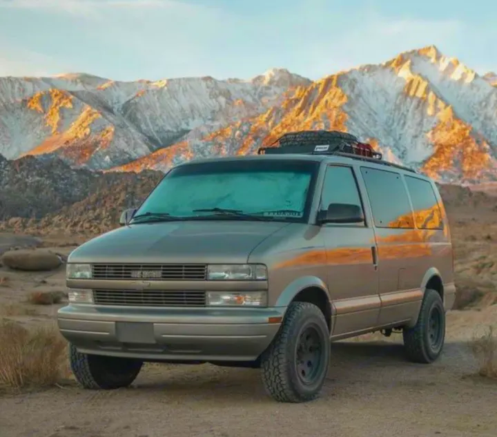 This rugged overland van, perfect for an RV rental adventure, is parked before snowy mountains. Great for outdoor travel!. Chevrolet Astro Van AWD 2003