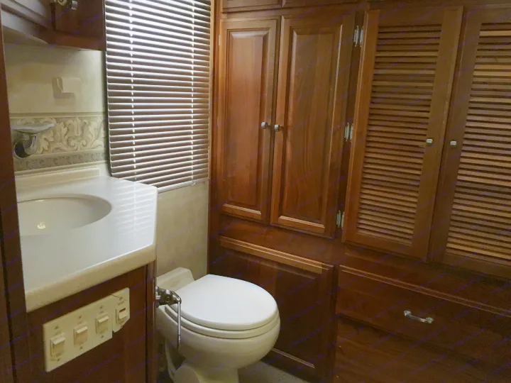 Functional RV rental bathroom with sink, toilet, and ample wood storage, including slatted cabinet doors.. Fleetwood Revolution Le 2005