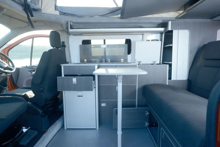 This rv rental features a modern interior with kitchen, flexible seating, ample storage, and a pop-top roof.. Ford Custom 2018