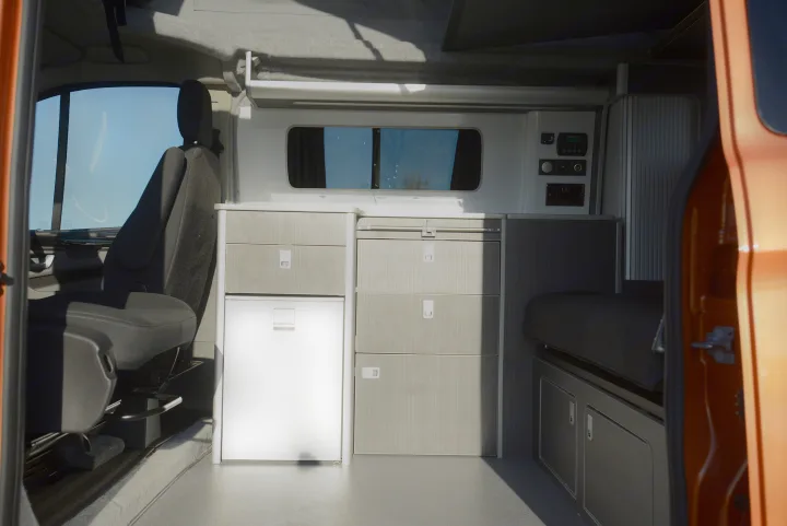 Sleek camper van interior with modular storage, fridge, and seating, perfect for an RV rental escape.. Ford Custom 2018