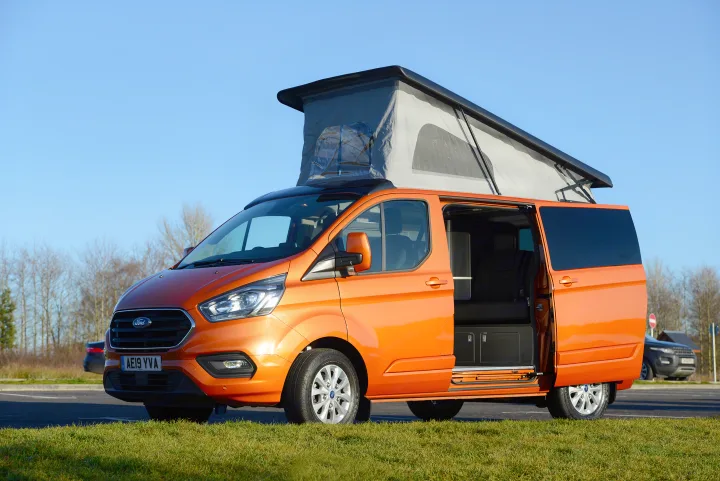 An orange Ford Transit Custom campervan with pop-top roof and open side door, ideal for rv rental adventures.. Ford Custom 2018