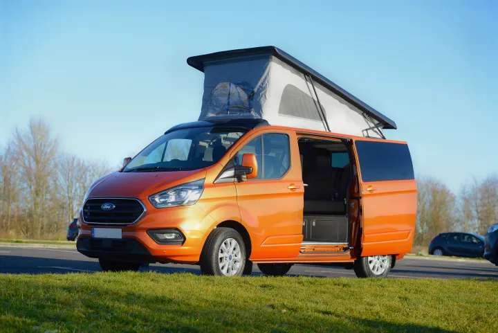 Orange Ford Transit Custom pop-top camper van for RV rental, with open side door, parked outdoors.. Ford Custom 2018