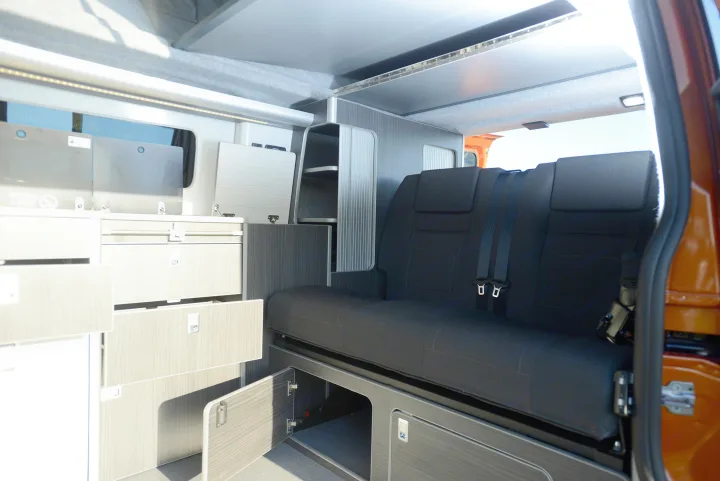 Inside a modern RV rental camper van with comfortable seating, ample storage cabinets, and a convenient pop-top roof.. Ford Custom 2018