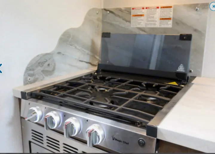 Compact Magic Chef stove in an RV rental kitchen, perfect for cooking on the go. Features oven & glass cover.. Forest River Other 2021