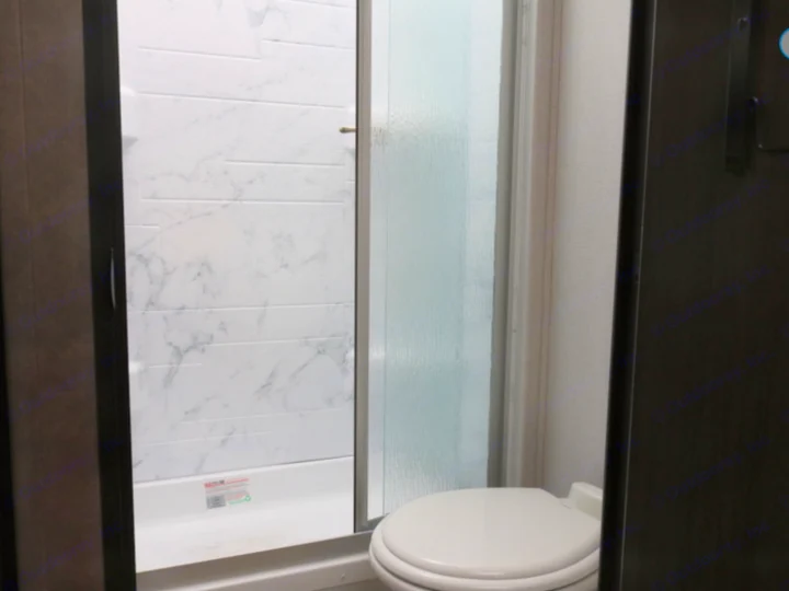 Compact RV rental bathroom featuring a modern shower with marble-look walls and a white toilet.. Forest River Other 2021