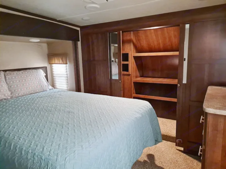 Spacious RV rental bedroom with large bed, wardrobe, & ample storage for comfortable travel.. Keystone Volante 3801MD 2018